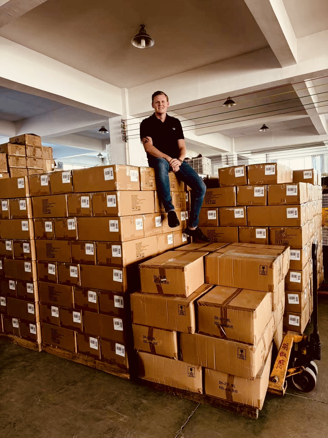 Lyden Smithers sitting on shipment boxes in a Chinese warehouse